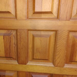 Close-up of a wooden door showing detailed geometric panel designs with rich wood grain textures.