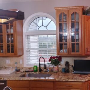 Traditional kitchen design with natural wood cabinets, granite countertops, and a large arched window.